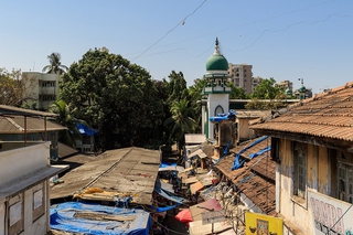 Image shows the tops of a market in Mumbai and the minaret of a mosque in the background.